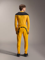 Alpinestars Limited Edition A-Supra Melt Gold Gear-Set, achteraanzicht van een model in donkergeel MTB-shirt met lange mouwen en zwart schouderstuk, donkergele broek met groot zwart Alpinestars-woordmerk op het achterpand, zwarte schoenen
