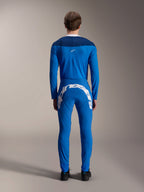 Mannelijk model van de achterkant in de A-Supra Melt Jersey - Lange Mouw in blauw, donkerblauw schouderpaneel met een klein wit sterlogo, bijpassende blauwe MTB-broek met grote witte Alpinestars-branding op de achterkant, gecoördineerde performance wieleroutfit voor mountainbiken.