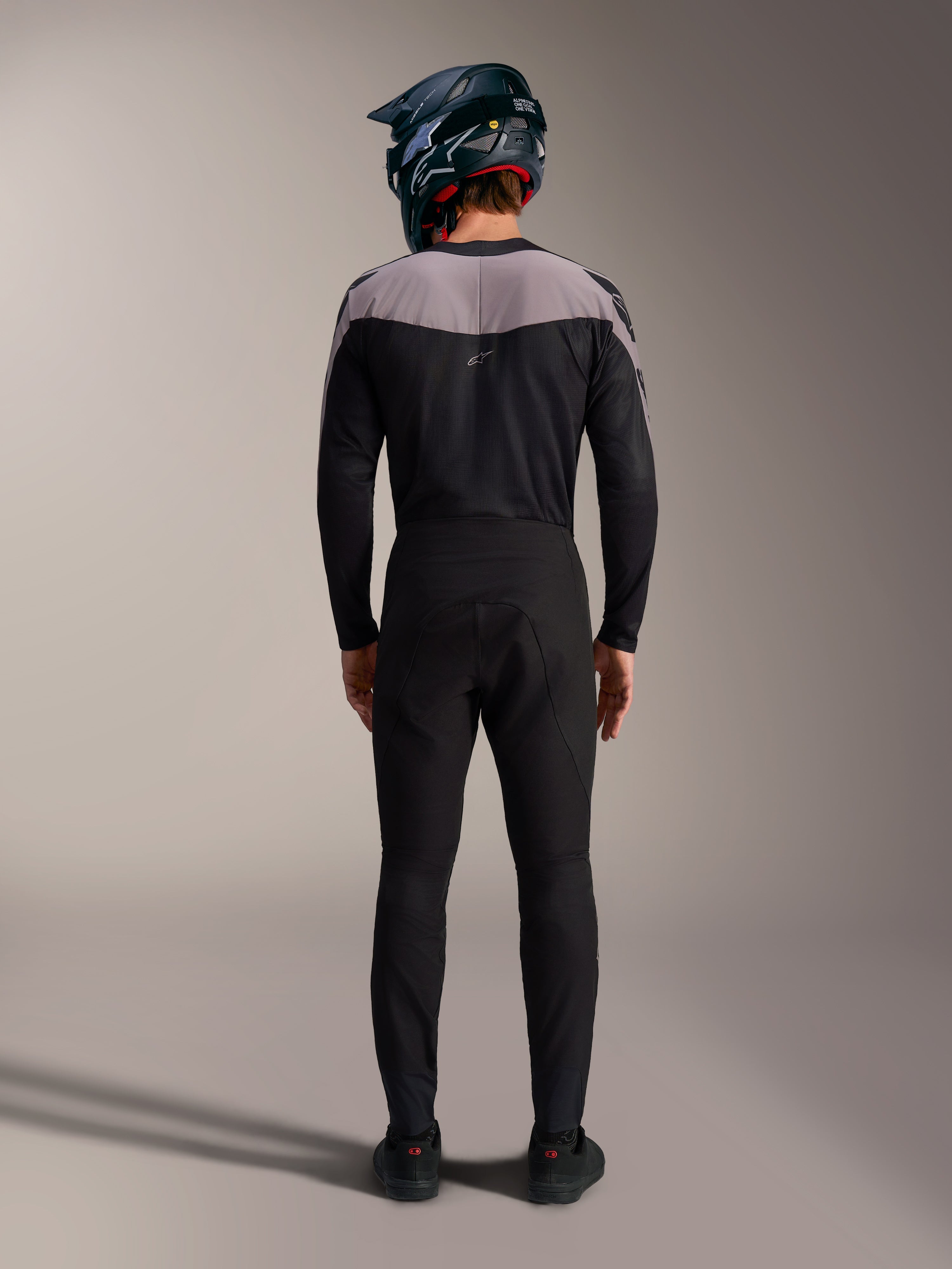 Zwarte Alpinestars A-Supra Elite MTB-kit met performance broek, jersey en full-face helm, achteraanzicht.