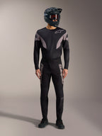 Zwarte A-Supra Elite MTB-kit met jersey met lange mouwen, racebroek met grijze logo's en integraalhelm.