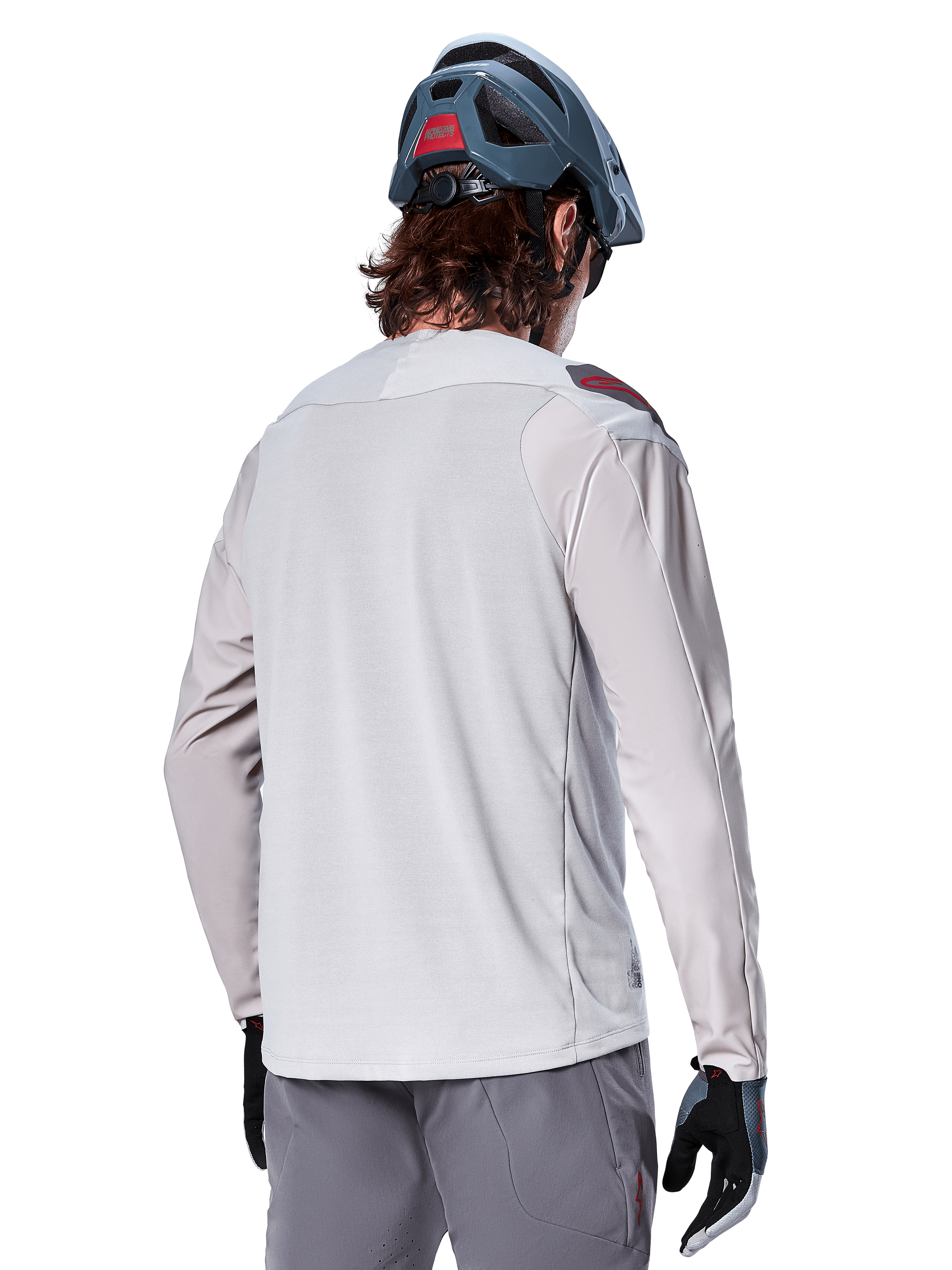 Alpinestars A-Aria Polartec Switch Long Sleeve Jersey, Light Gray, seen from the back on a rider, worn with a blue mountain bike helmet and gray pants, performance mountain bike apparel for off-road trails