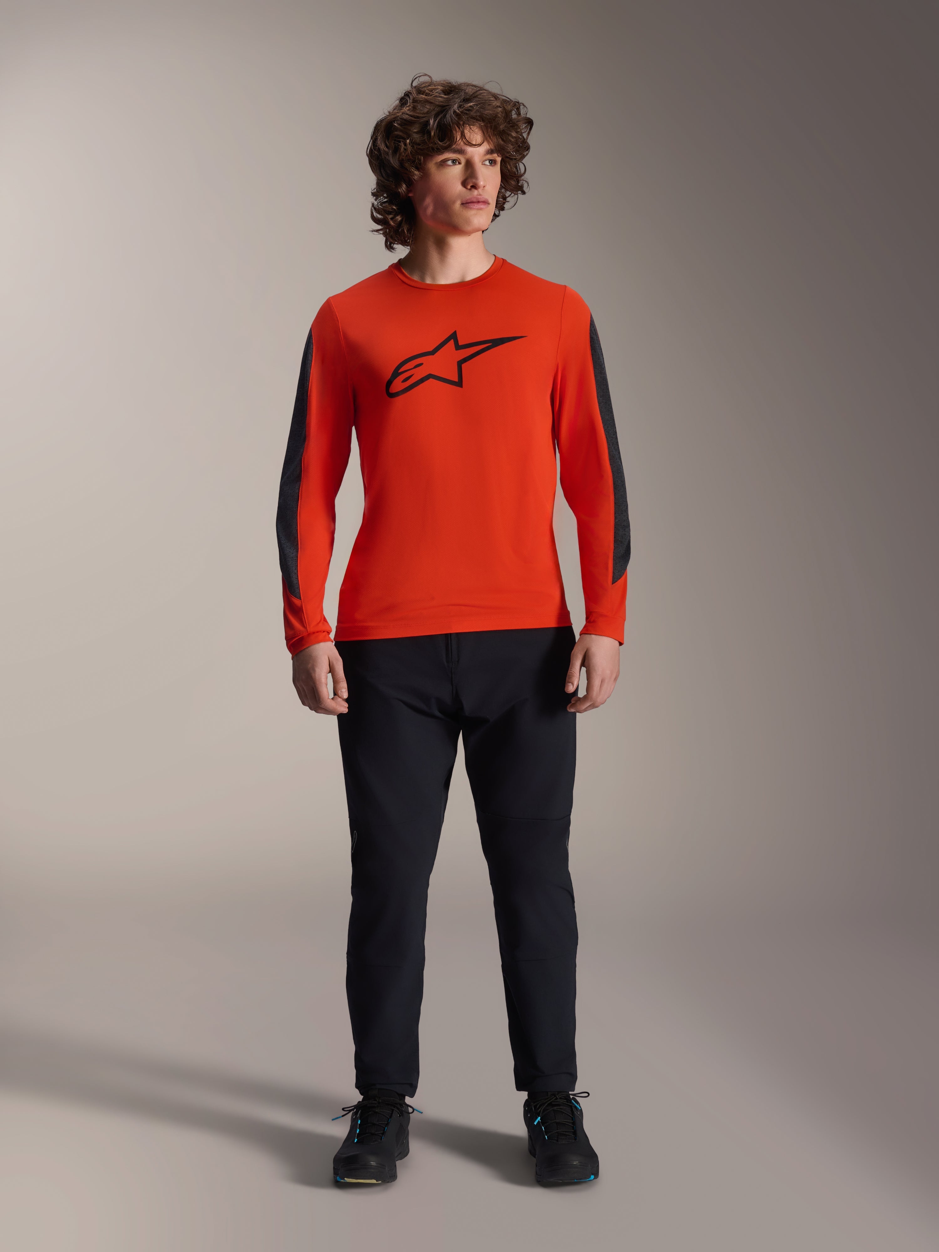 Alpinestars A-Dura Insert Astar Jersey - lange mouwen, Spicy Orange met zwart Astar-logo en donkergrijze mouwpanelen, gedragen met zwarte mountainbikebroek en schoenen, duurzame textielconstructie voor off-road rijden