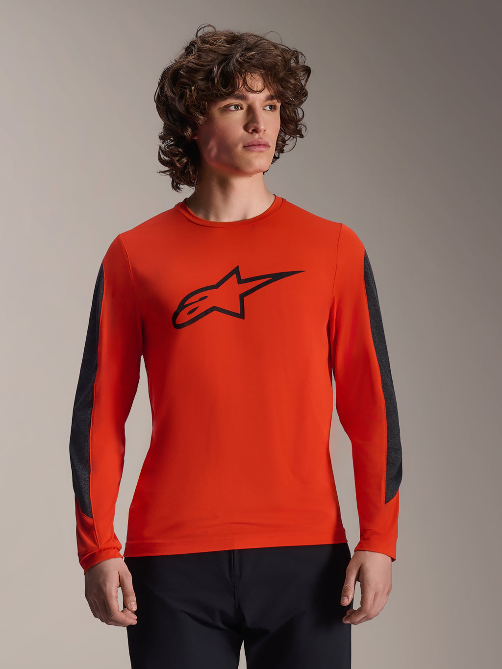 Alpinestars A-Dura Insert Astar Jersey met lange mouwen, Spicy Orange met zwart Astar-logo, voorzien van donkergrijze duurzame mouwinzetten, gedragen door een mannelijk model, performance MTB-fietskleding