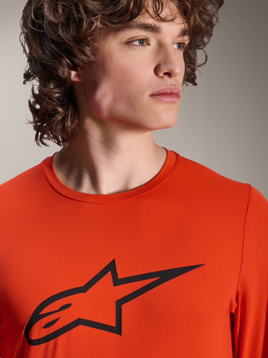 Alpinestars A-Dura Insert Astar Jersey, MTB-jersey met lange mouwen, Spicy Orange, met zwart Alpinestars Astar-logo op de borst, close-up van een mannelijk model