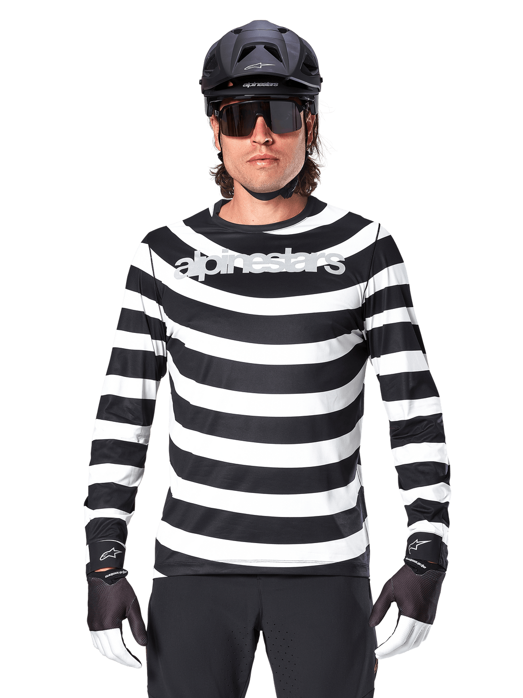 Alpinestars A-Aria Oscar Jersey met lange mouwen, zwart-wit horizontaal gestreept, reflecterend Alpinestars-logo op de borst, mannelijke fietser met zwarte MTB-helm, fietszonnebril en performance handschoenen