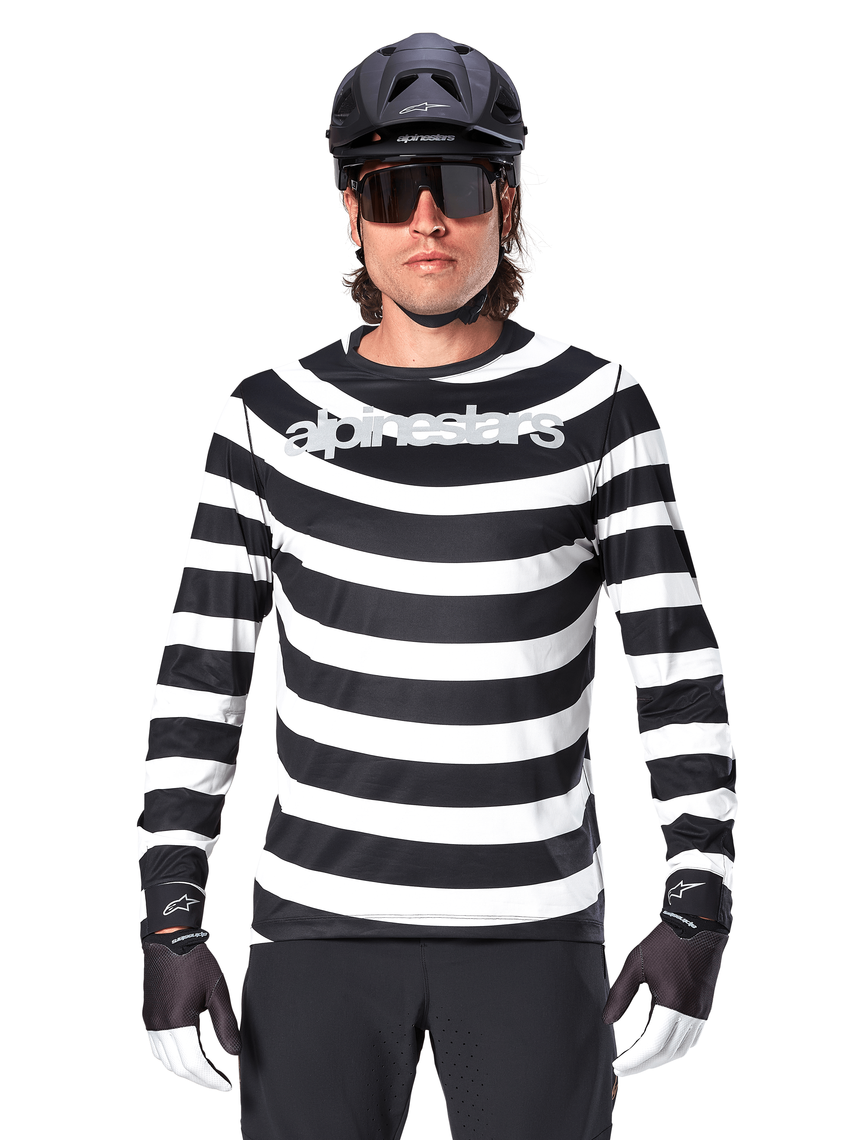 Alpinestars A-Aria Oscar Jersey met lange mouwen, zwart-wit horizontaal gestreept, reflecterend Alpinestars-logo op de borst, mannelijke fietser met zwarte MTB-helm, fietszonnebril en performance handschoenen