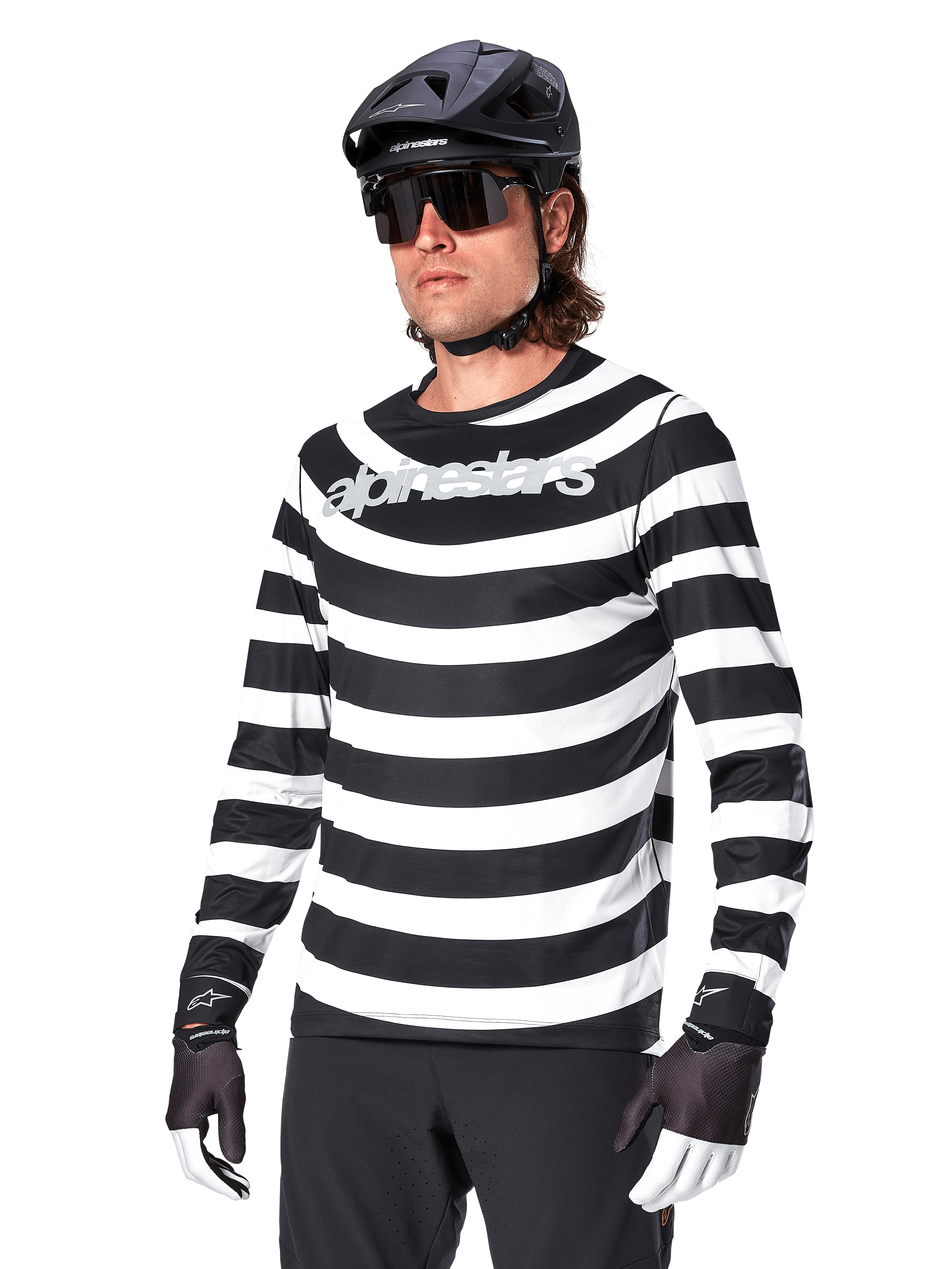 Alpinestars A-Aria Oscar Jersey met lange mouwen, MTB-wielershirt, zwart-witte horizontale strepen, gedragen met een zwarte helm en zonnebril, voorzien van Alpinestars-branding op de borst, technische mountainbike-kleding