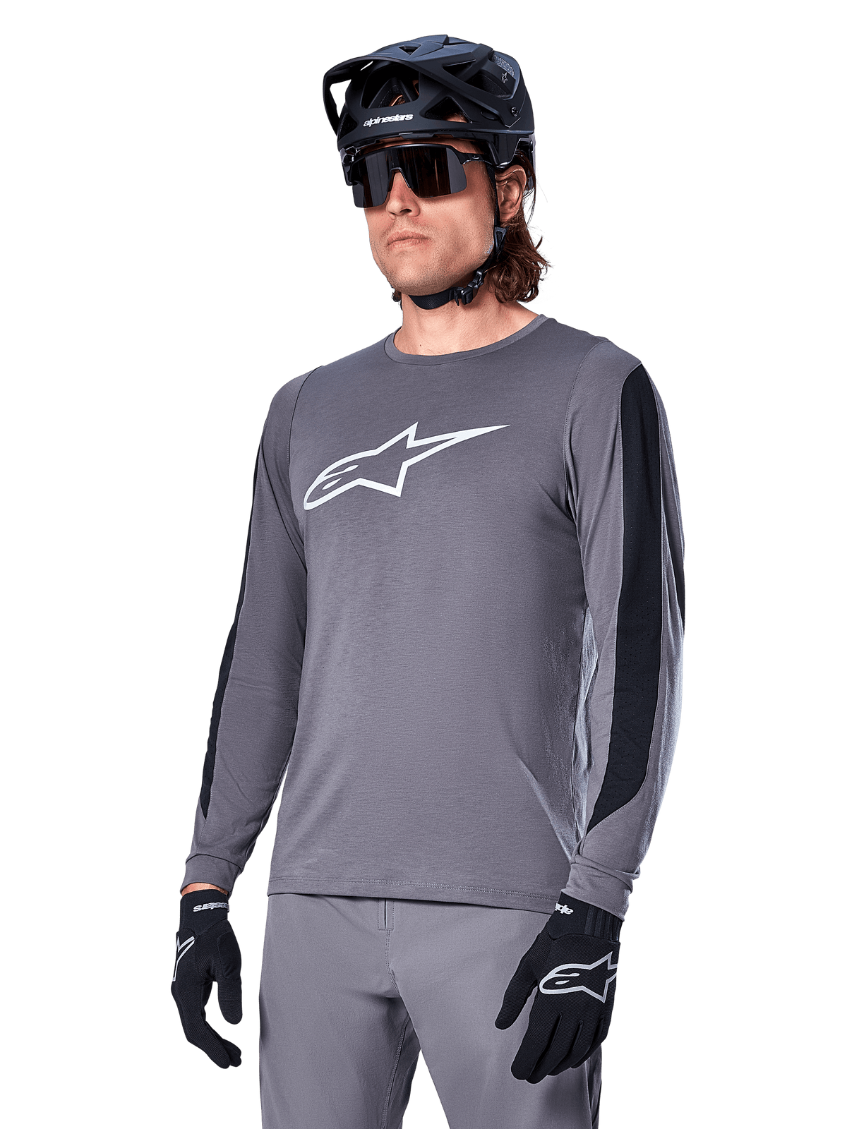 Alpinestars A-Dura Dri Astar Jersey Long Sleeve, Dark Gray with white chest logo and black mesh side panels, MTB mountain biking jersey, worn with black helmet, sunglasses, and matching gray pants