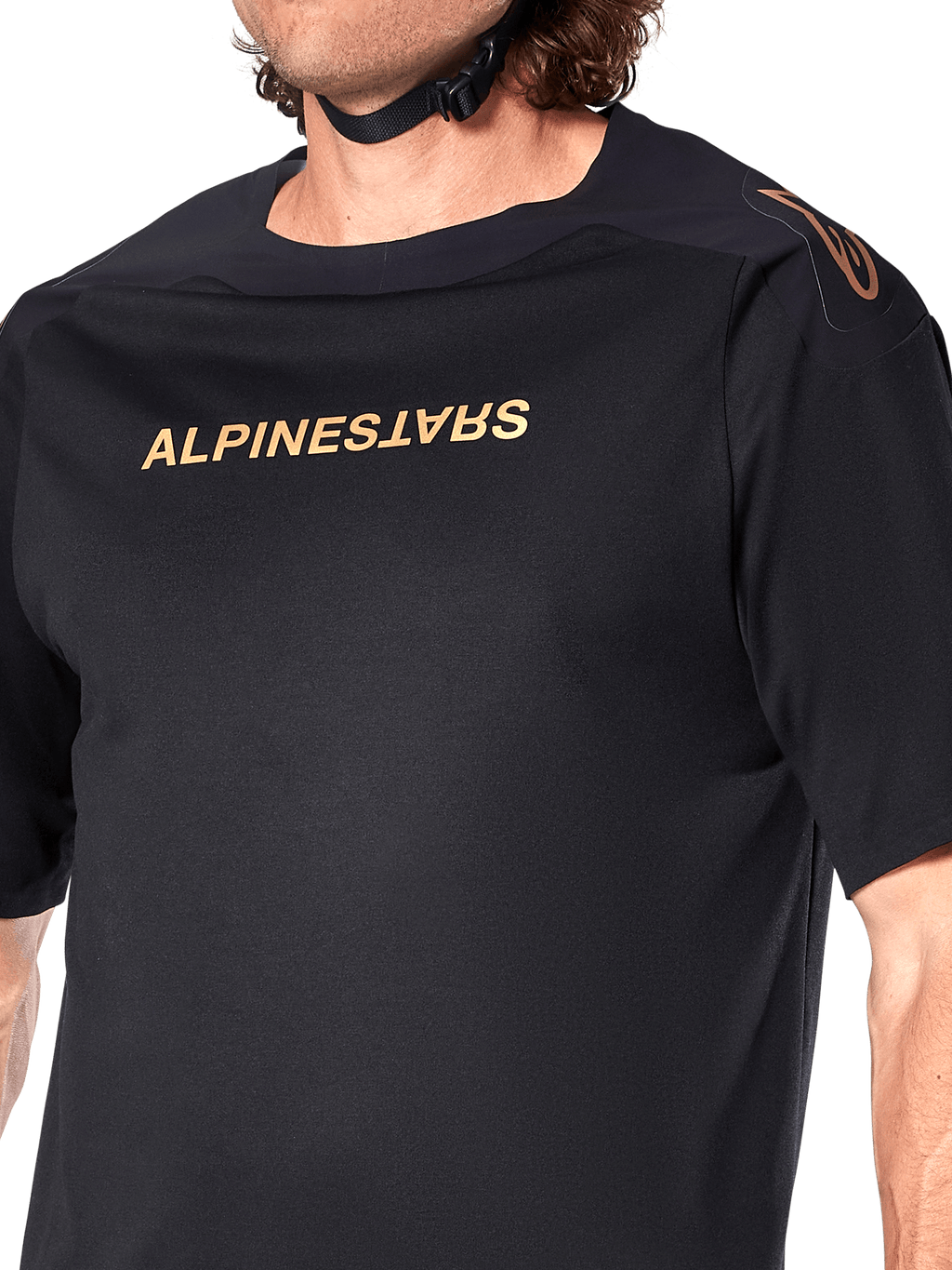 Alpinestars A-Aria Polartec Switch Jersey, MTB-jersey met korte mouwen, zwart, gouden Alpinestars-belettering op de borst en logo op de schouder, close-up van het bovenlichaam met focus op de technische stof en prestatiegerichte pasvorm