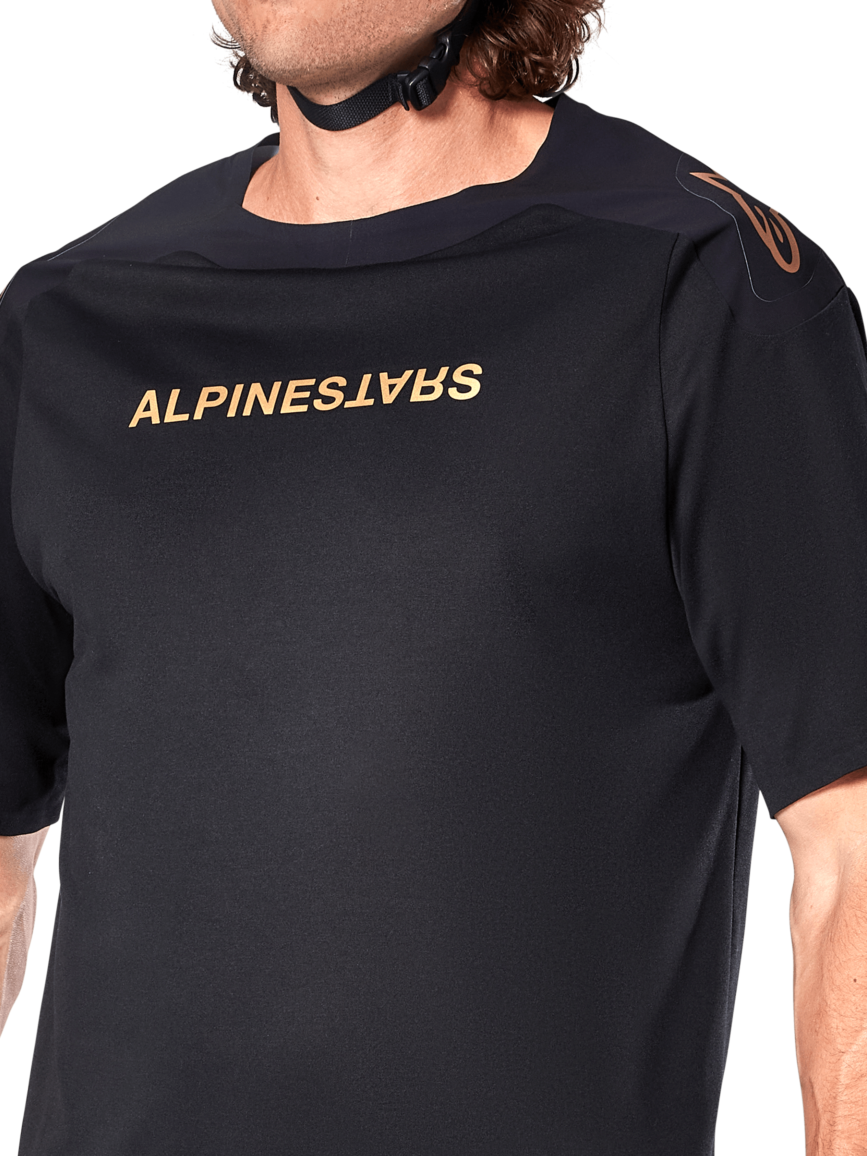 Alpinestars A-Aria Polartec Switch Jersey, MTB-jersey met korte mouwen, zwart, gouden Alpinestars-belettering op de borst en logo op de schouder, close-up van het bovenlichaam met focus op de technische stof en prestatiegerichte pasvorm