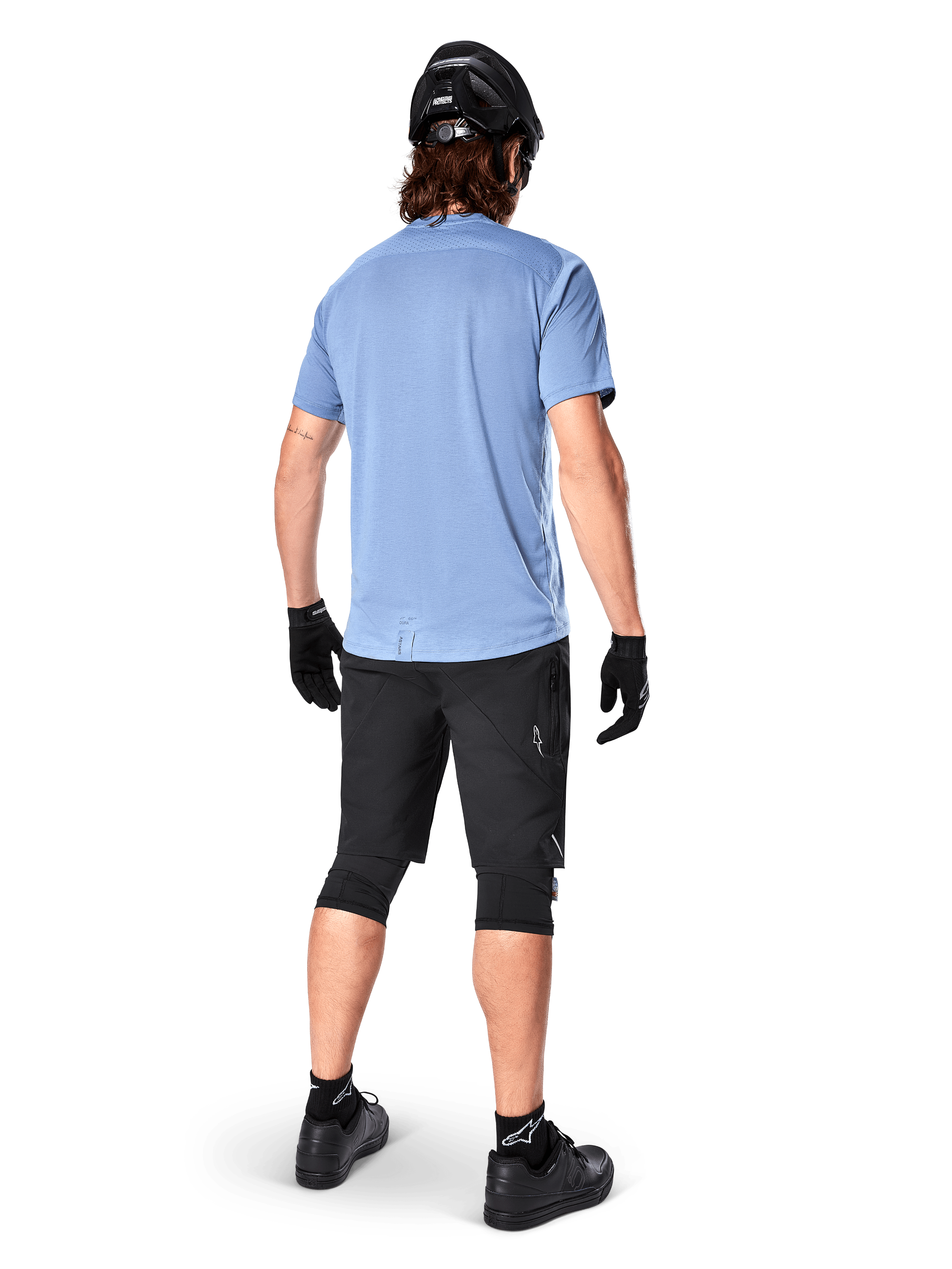 Alpinestars A-Dura Dri Astar Short Sleeve Jersey, Infinity Blue, rear view, paired with black mountain bike shorts and helmet, technical cycling apparel with moisture-wicking fabric and drop tail