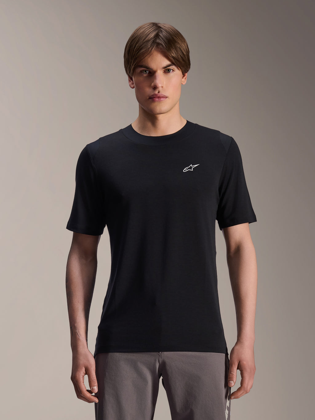 Alpinestars A-Dura Dri Wool Jersey met korte mouwen, zwart, gedragen door een mannelijk model, klein wit Alpinestars-logo op de borst, performance fietskleding voor MTB-trailritten, vochtafvoerende drirelease® wolstof