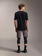 Alpinestars A-Dura Elite Shorts, donkergrijze mountainbike short, achteraanzicht, gedragen met een zwart jersey met korte mouwen, kniebeschermers en zwarte sokken, technische wielerkleding voor off-road rijden