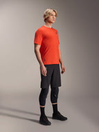 Alpinestars A-Aria Astar jersey met korte mouwen in Spicy Orange, gedragen door een model met een zwarte MTB-short en kniebescherming, lichtgewicht ademende mountainbikekleding, levendig oranje met minimale zwarte branding
