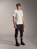 Alpinestars A-Aria Astar Jersey, korte mouwen, ecru, voorzien van een zwart logo op de borst, gedragen met een zwarte fietsbroek en kniebeschermers, lichtgewicht MTB-performancekleding