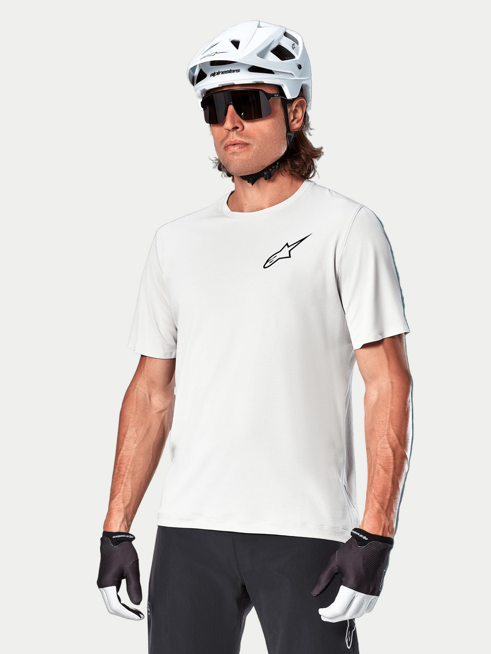 Alpinestars A-Aria Astar Jersey met korte mouwen, White Dove, gedragen door een fietser met een witte helm en donkere zonnebril, voorzien van een klein zwart ster-logo op de borst, ademende performance-kleding voor mountainbiken