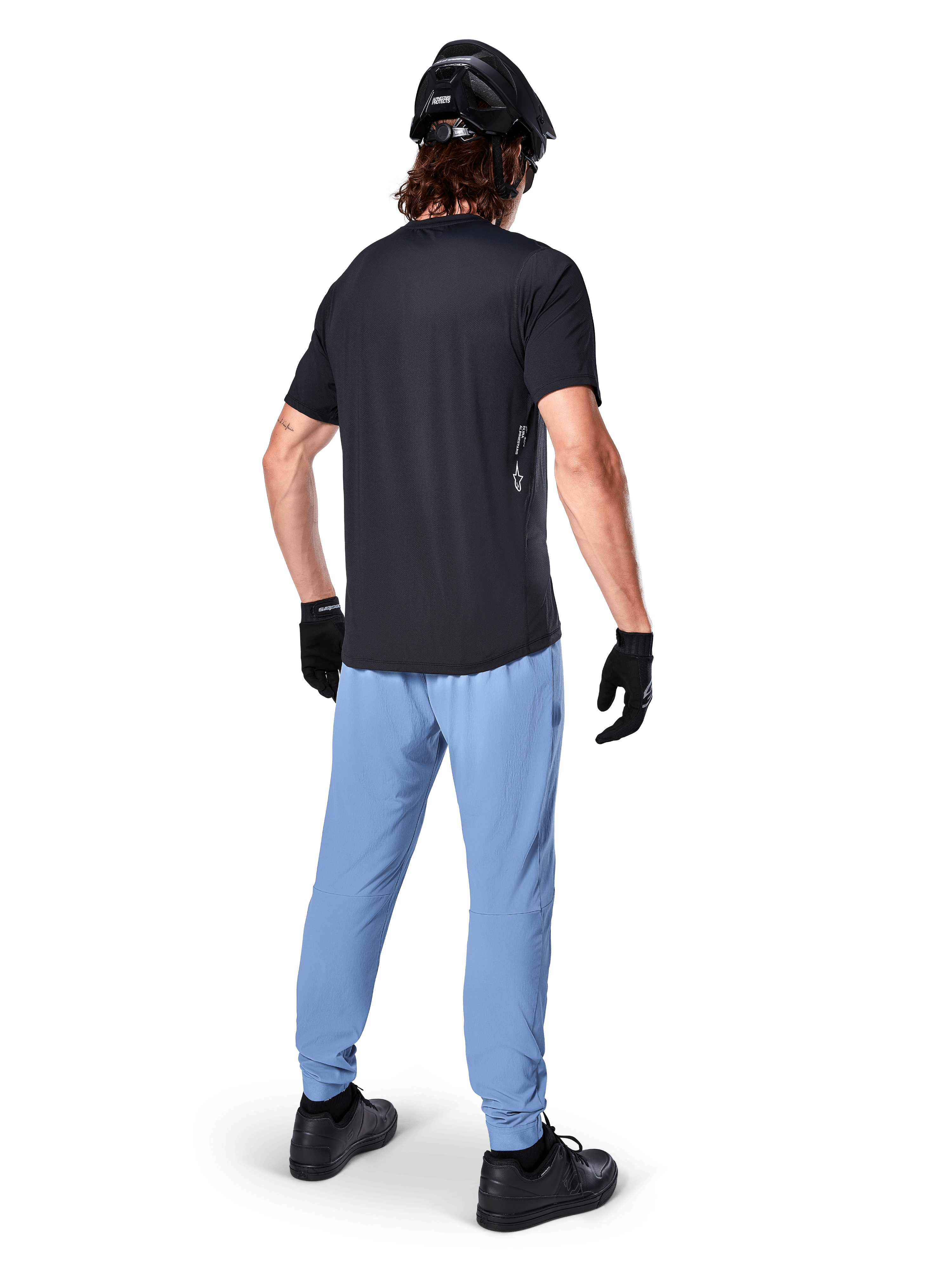 Alpinestars A-Dura Oscar Jersey - Short Sleeve, Black, Rear view of rider wearing a black mountain bike jersey, paired with light blue pants, black helmet, and black gloves, technical MTB apparel for off-road performance