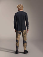Alpinestars A-Dura Camo broek, mountainbikebroek, bruin camouflagepatroon, achteraanzicht, gedragen met een zwarte jersey met lange mouwen en zwarte sneakers, regular fit textiele broek voor off-road fietsen