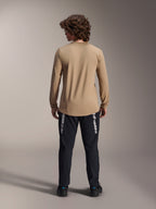Alpinestars A-Dura Astar Jersey met lange mouwen, lichtbruin, achteraanzicht met de langere drop tail, gedragen met een zwarte broek voorzien van Alpinestars-branding, hoogwaardige mountainbike-kleding