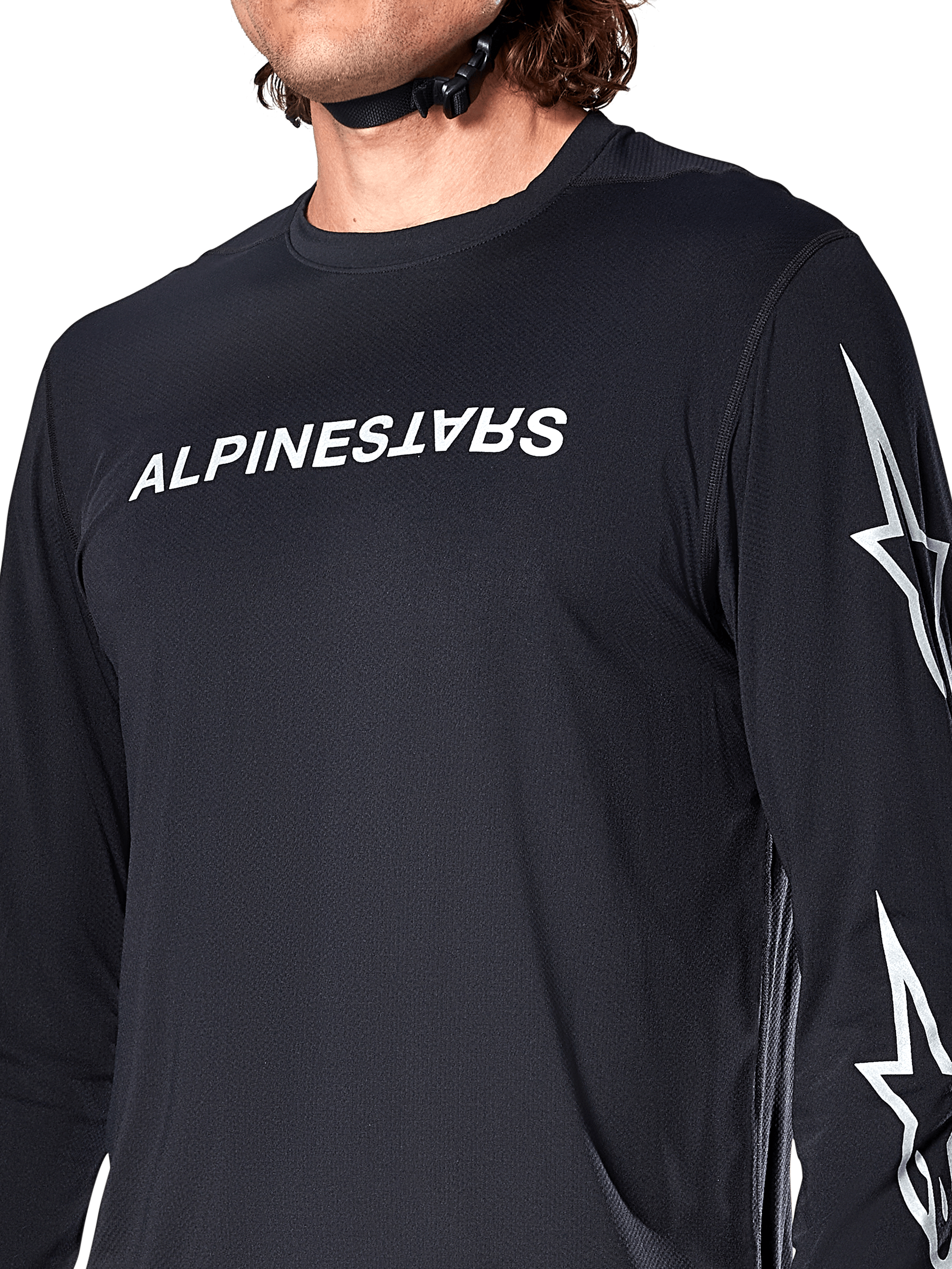Alpinestars A-Dura Switch Long Sleeve Jersey, Black, featuring white Alpinestars wordmark on the chest and star logos on the sleeve, worn by a rider with a helmet strap visible, technical mountain bike apparel.