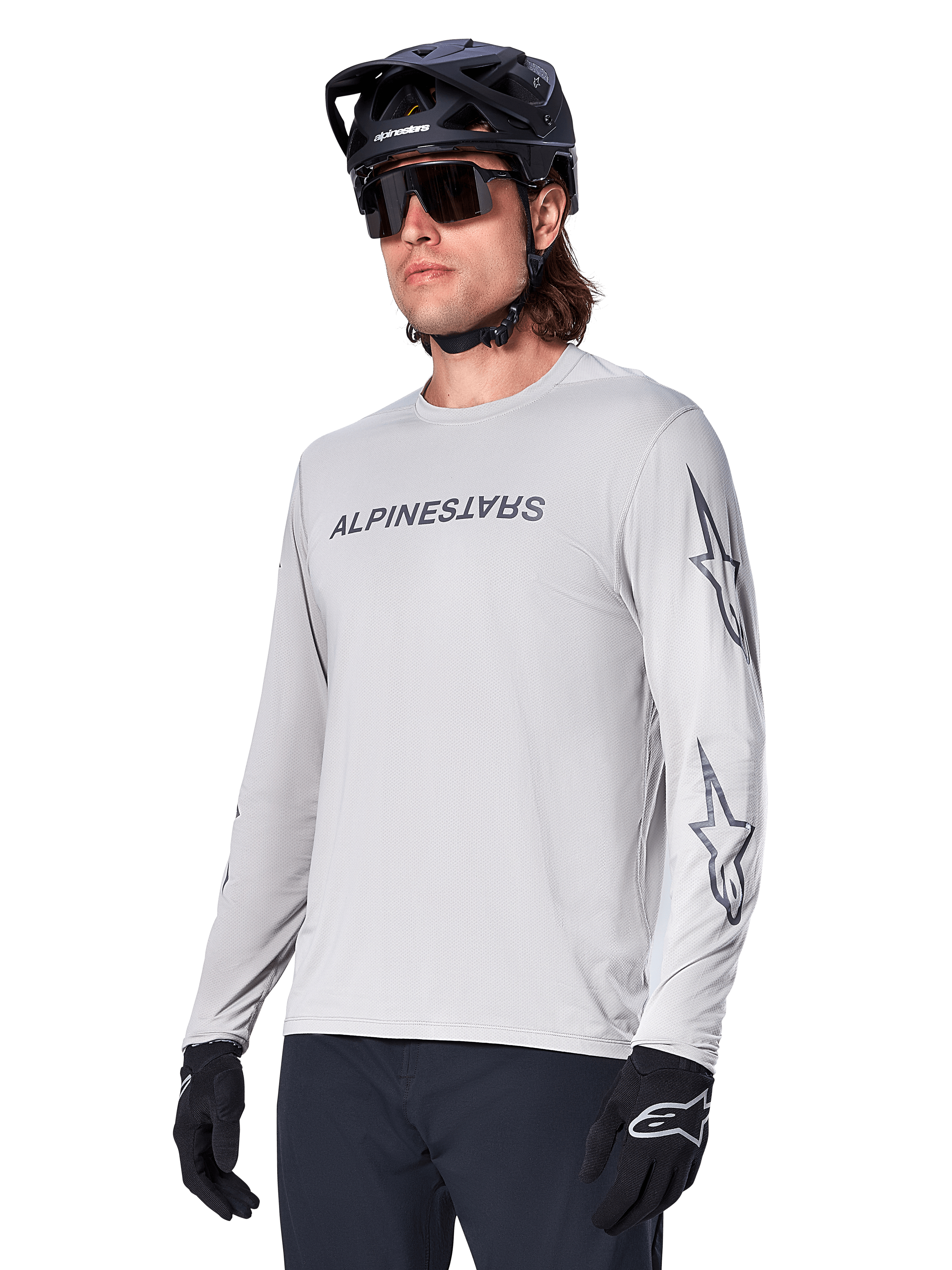Alpinestars A-Dura Switch Long Sleeve Jersey, Mountain Bike Jersey, Light Gray, black wordmark screen print on chest and star logos on sleeves, worn with black mountain bike helmet, dark sunglasses, and black gloves, athletic off-road cycling gear