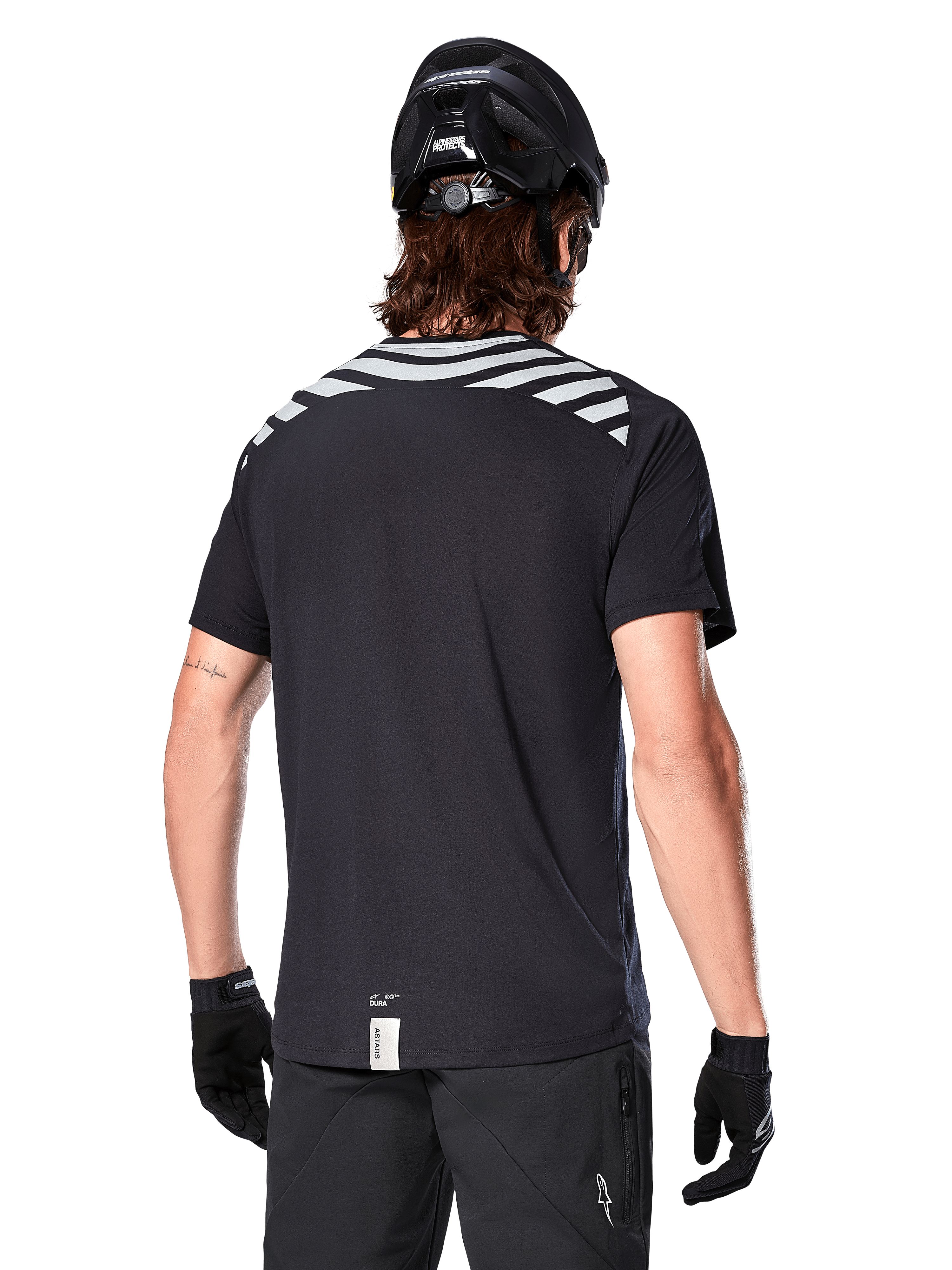 Alpinestars A-Dura Dri Oscar Jersey, MTB-jersey met korte mouwen, Black Reflective, achteraanzicht op model met fietshelm en handschoenen, met reflecterende grijze schouderstrepen en een verlengd achterpand, vochtafvoerende technische stof voor mountainbiken