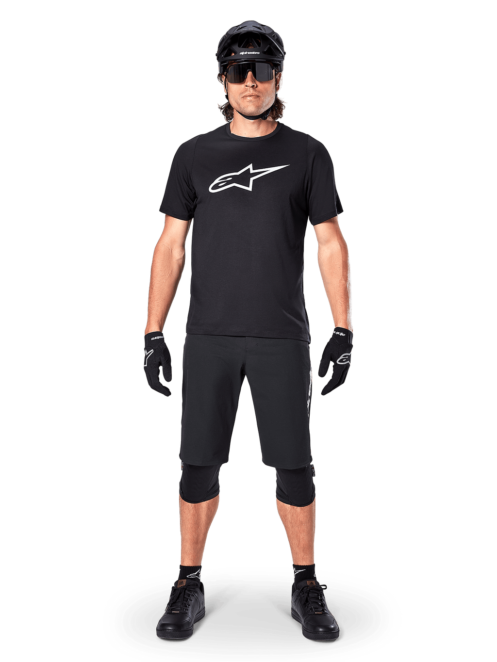 Alpinestars A-Dura Dri Oscar jersey met korte mouwen, Black Reflective, gedragen met bijpassende zwarte MTB-short, handschoenen, kniebeschermers en helm, groot wit Alpinestars-logo op de borst, complete mountainbike-outfit