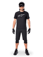 Alpinestars A-Dura Dri Oscar jersey met korte mouwen, Black Reflective, gedragen met bijpassende zwarte MTB-short, handschoenen, kniebeschermers en helm, groot wit Alpinestars-logo op de borst, complete mountainbike-outfit