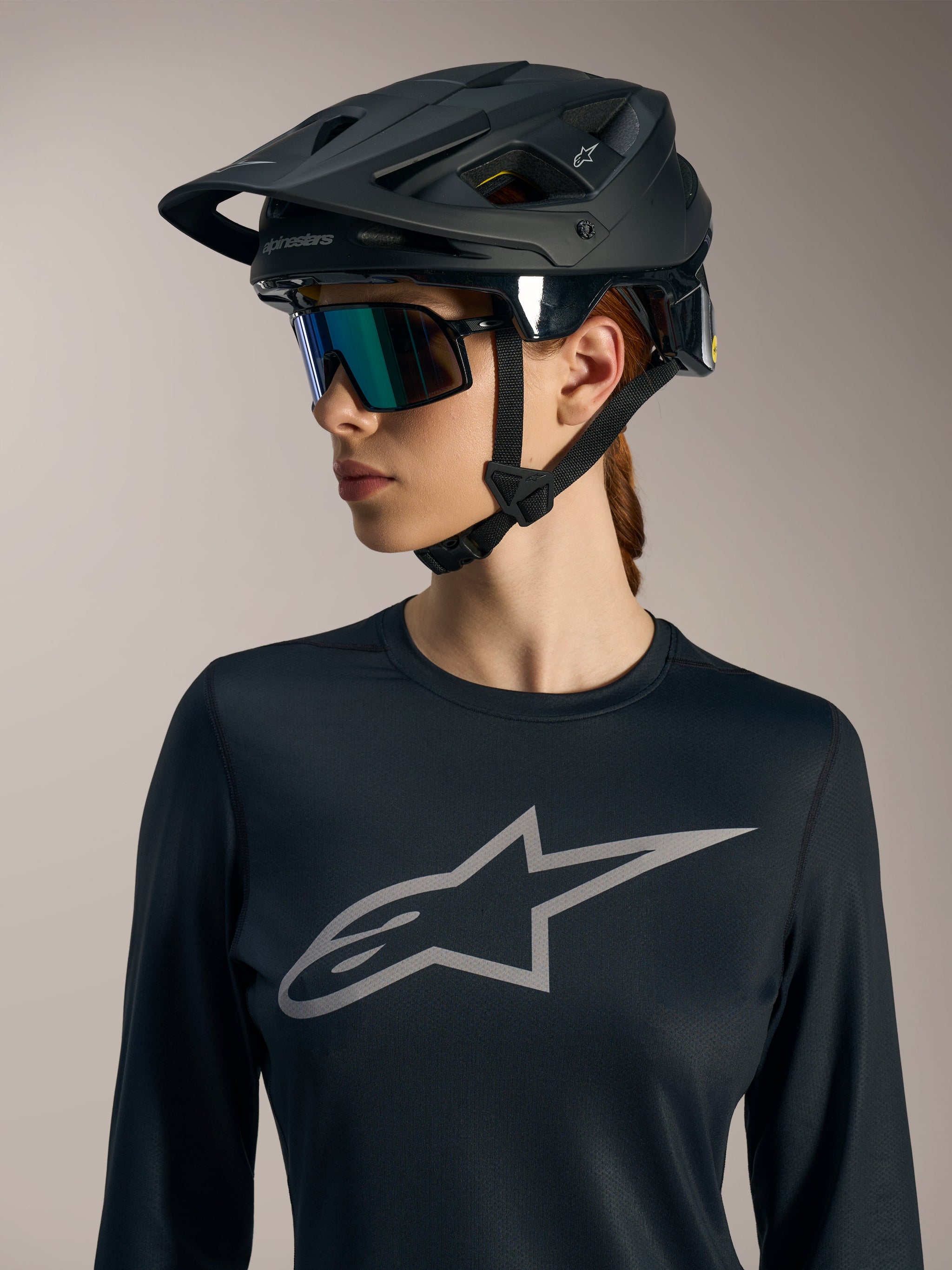Zwarte Stella A-Dura Ride LS jersey voor dames met grijs Astars-logo op de borst en matzwarte MTB-helm.