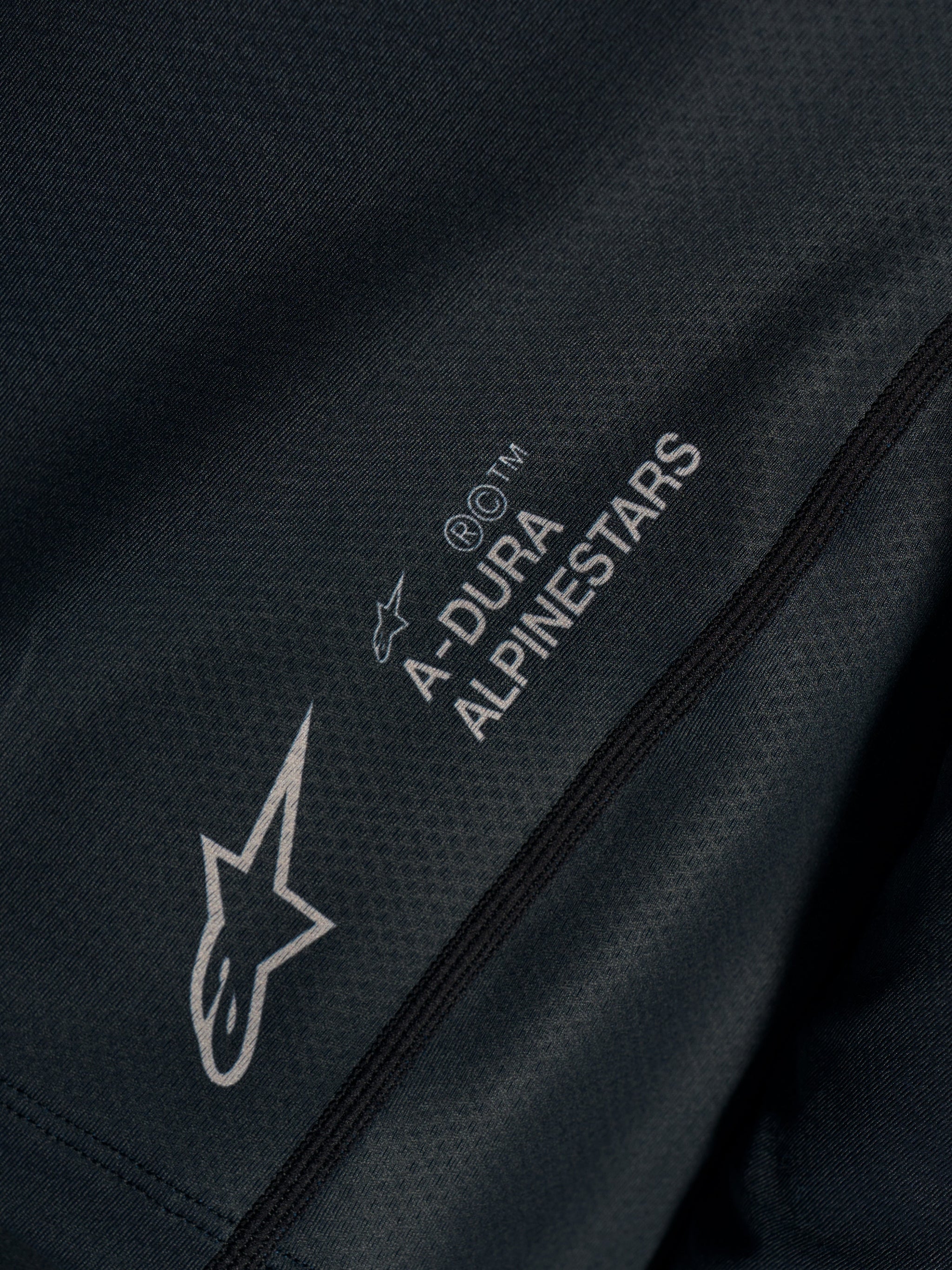 Zwarte Stella A-Dura Ride Jersey close-up met technische jacquard stof en A-DURA ALPINESTARS en Astars logo's.