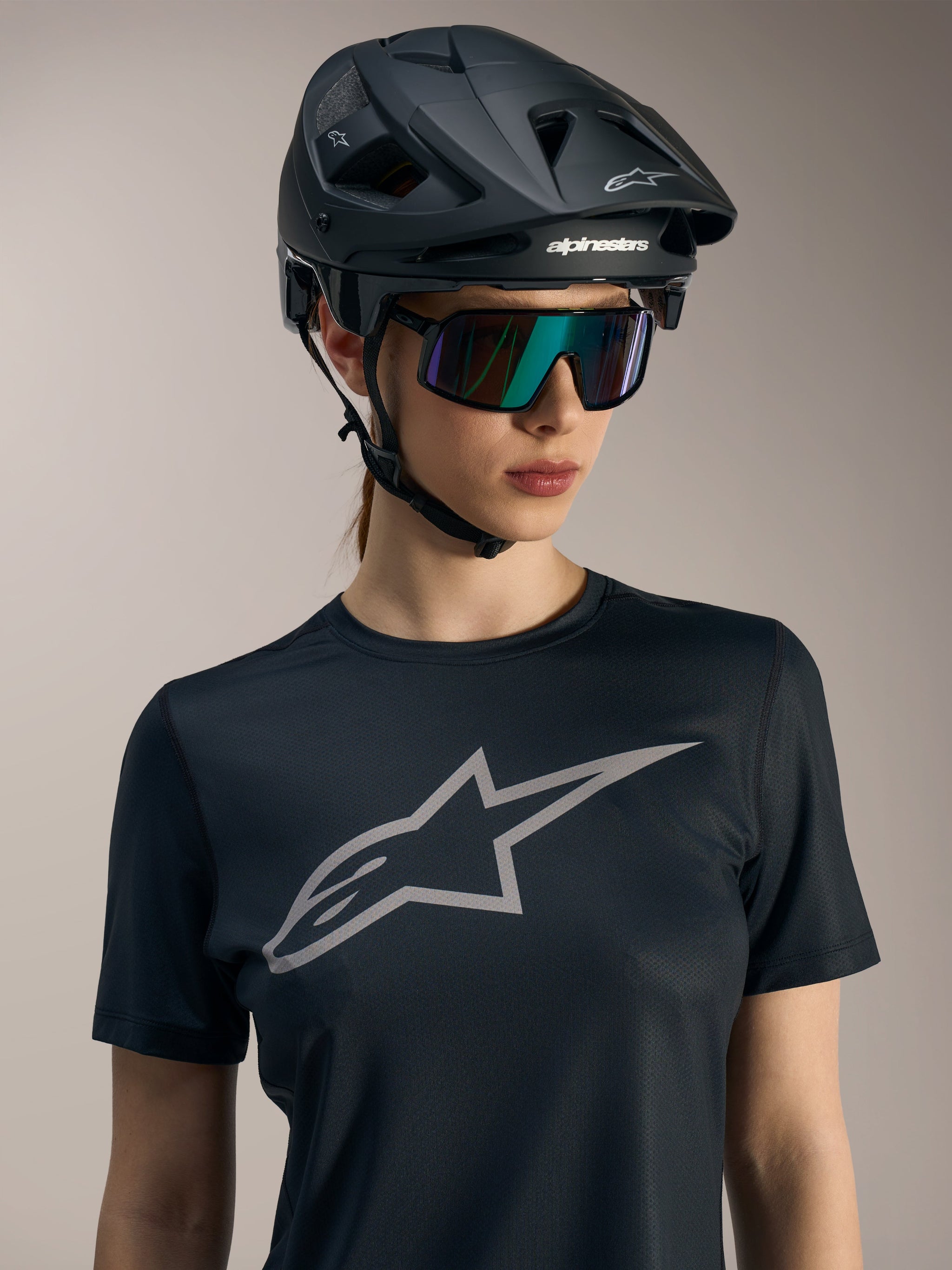 Zwarte Stella A-Dura Ride jersey voor dames, grijs logo op de borst, gedragen met een MTB-helm en zonnebril.