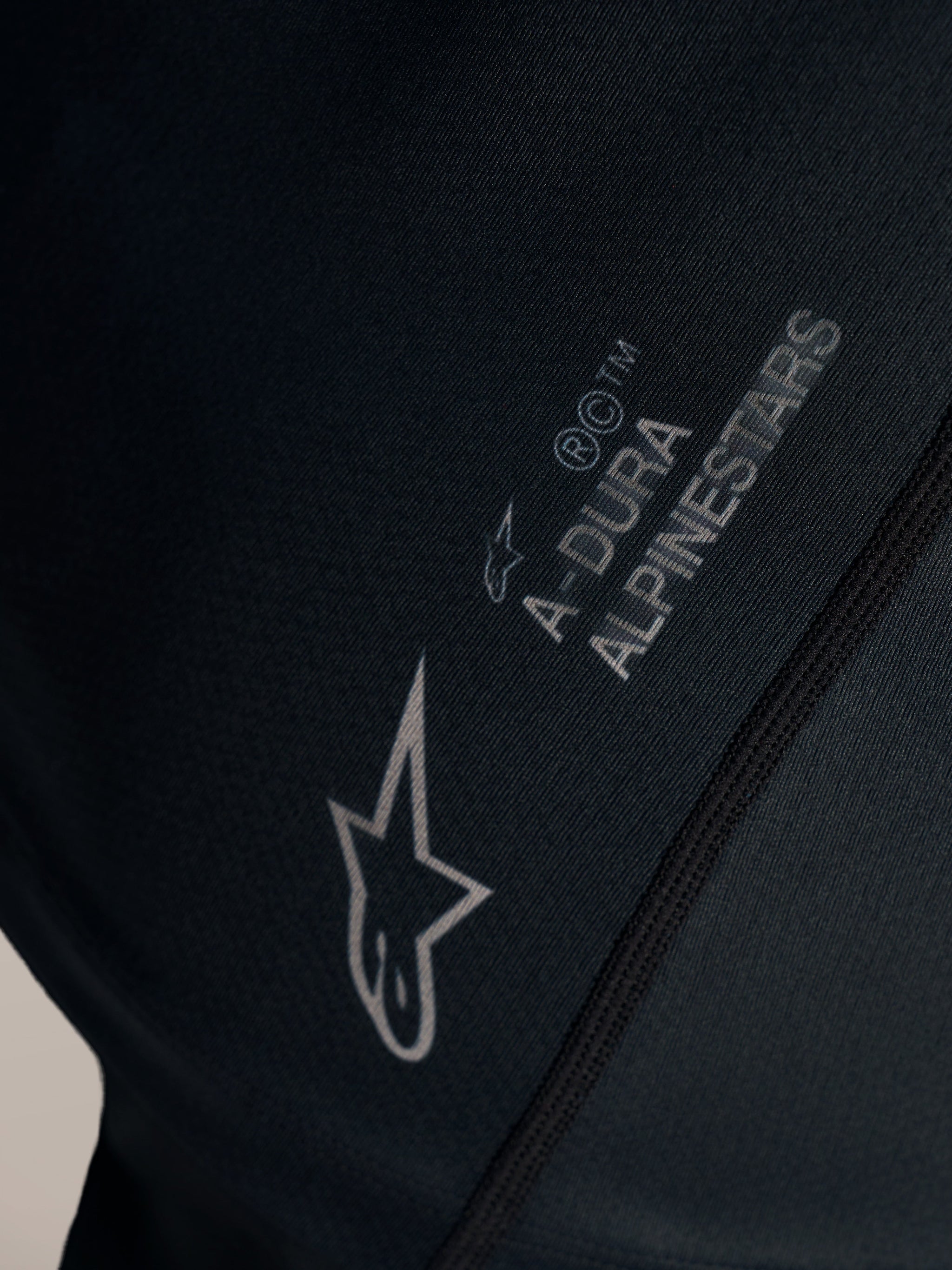 Detail van de zwarte Stella A-Dura Ride Jersey met wit Alpinestars-logo en A-DURA branding op jacquardstof.