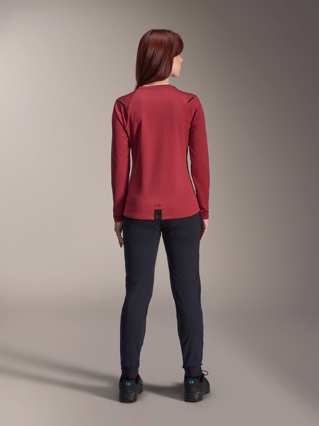 Alpinestars Stella A-Dura Thermal broek, mountainbikebroek voor dames, zwart, gedragen met een bordeauxrode jersey met lange mouwen, achteraanzicht dat de technische pasvorm en constructie voor fietsen in koud weer toont.