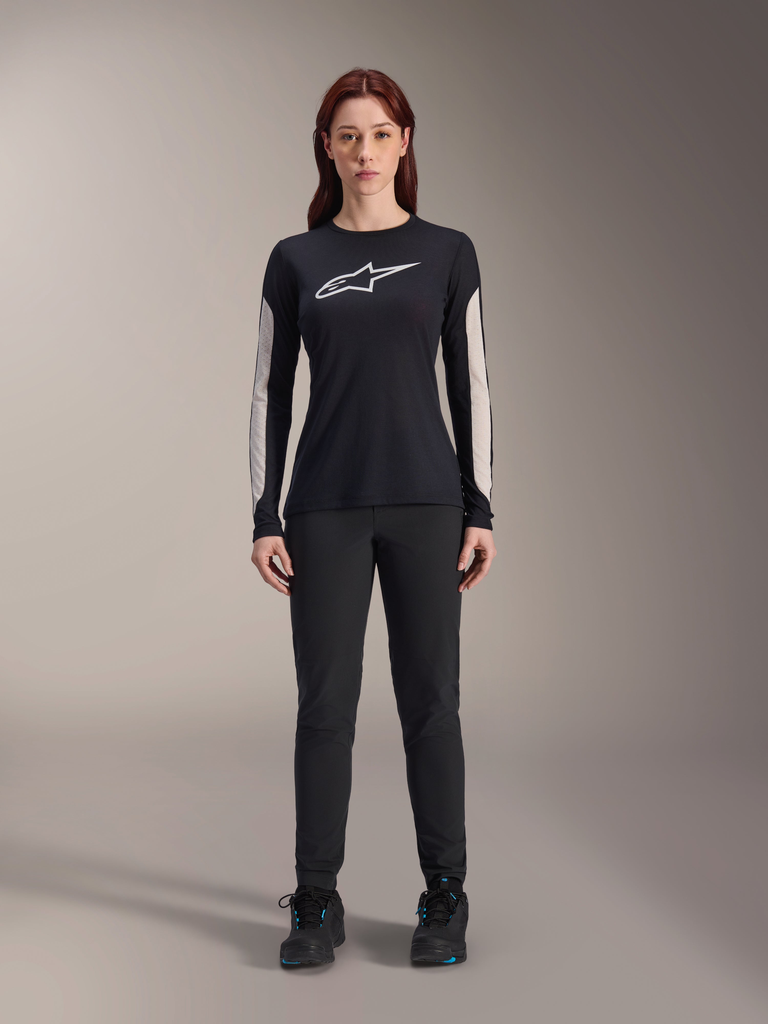 Alpinestars Stella A-Dura damesbroek, zwarte MTB-broek, met een specifieke damespasvorm en een gestroomlijnd ontwerp, gecombineerd met een zwart shirt met lange mouwen en zwarte fietsschoenen, duurzame uitrusting voor off-road mountainbiken