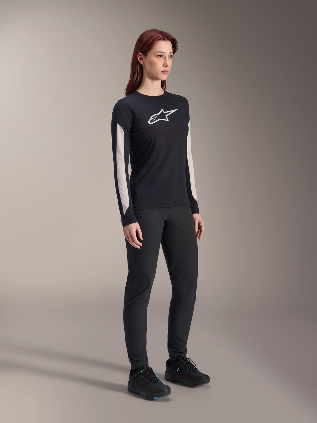 Alpinestars Stella A-Dura Dri Astar Jersey voor dames met lange mouwen, zwart, met witte mesh mouwpanelen en wit Astar-logo, gedragen met zwarte broek en schoenen, technische wielerkleding voor mountainbiken