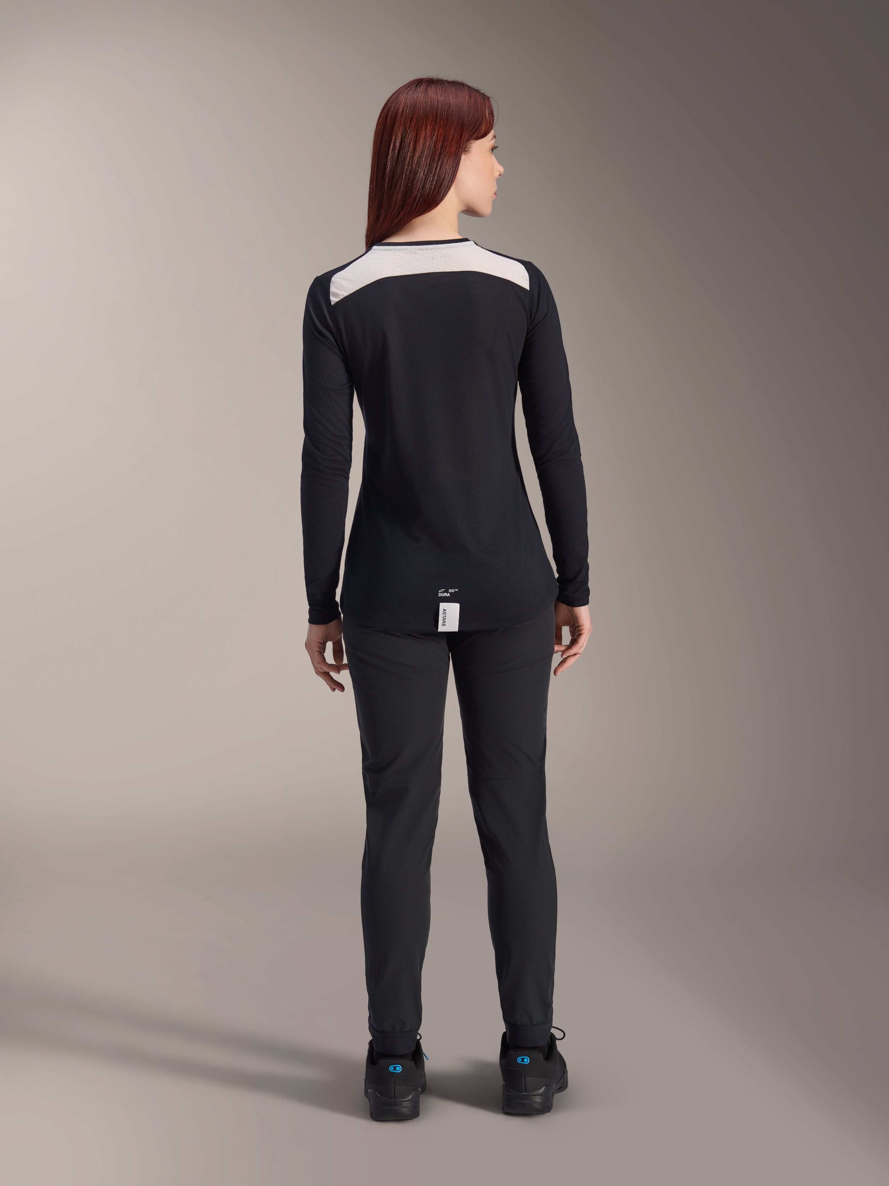 Alpinestars Stella A-Dura damesbroek en Stella A-Dura Elite jersey, MTB-uitrusting, zwart met wit schouderpaneel, van achteren gezien, technische outdoor kleding voor mountainbiken, gecombineerd met zwarte schoenen