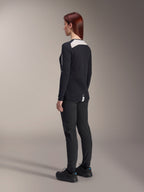 Vrouwelijke rijder in Alpinestars Stella A-Dura damesbroek en Stella A-Dura Elite jersey, zwart, achteraanzicht met witte mesh schouderpanelen op de jersey met lange mouwen, slim-fit technische broek, gecoördineerde mountainbike-uitrusting.