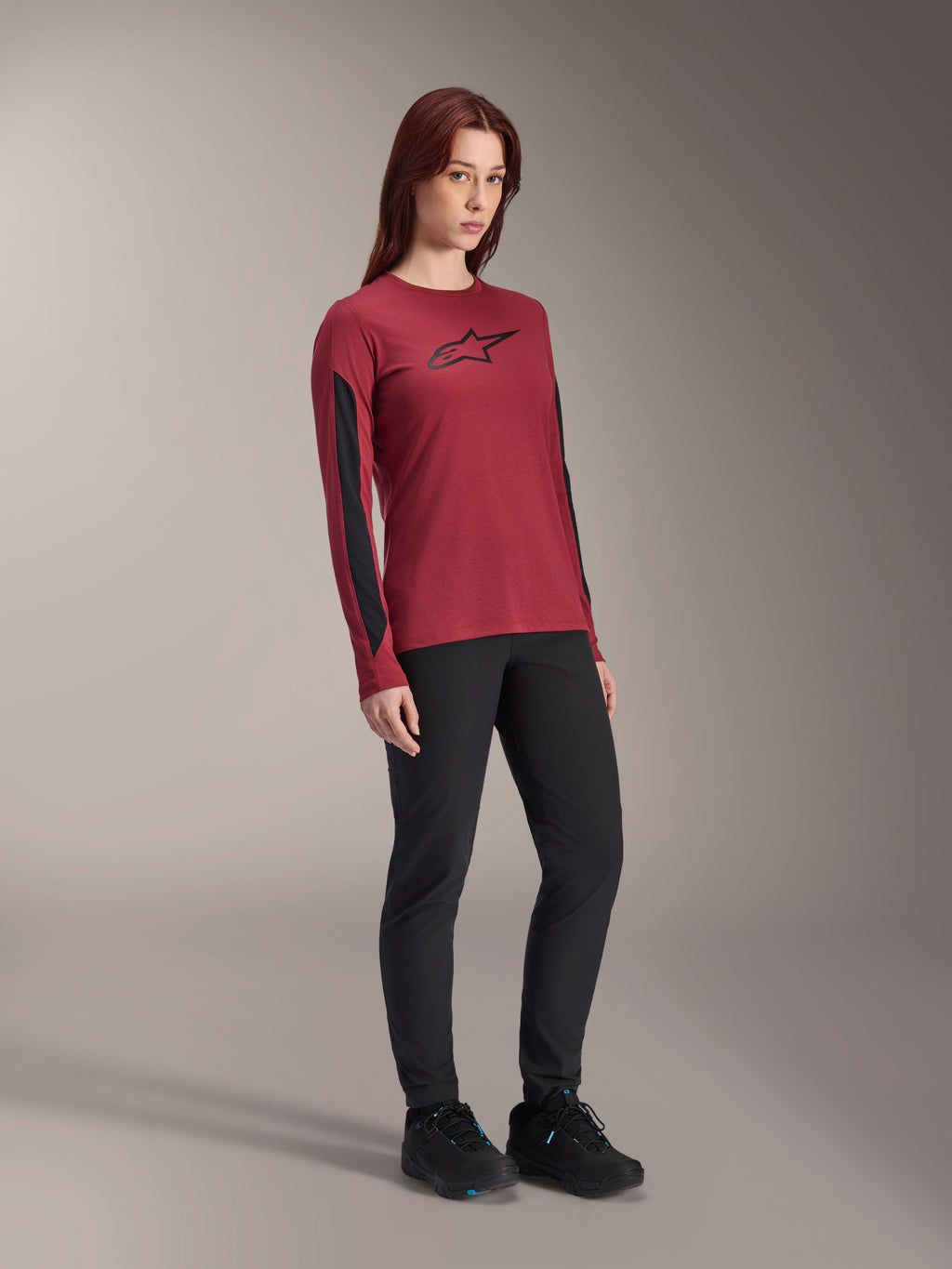 Alpinestars Stella A-Dura Dri Astar Jersey met lange mouwen voor dames, bordeauxrood met zwart logo op de borst en zwarte mesh-panelen op de mouwen, gedragen met een zwarte technische broek en zwarte fietsschoenen, hoogwaardige mountainbike-kleding voor dames