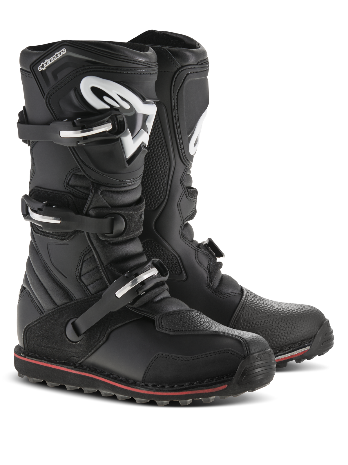 Alpinestars Tech-T laarzen, trial motorlaarzen, zwart met rode en witte accenten, voorzien van een sluitingssysteem met drie gespen, ergonomische scheenplaat met wit Astars-logo, dunne rode streep langs de zool, duurzame lederen constructie voor trial- en off-roadgebruik
