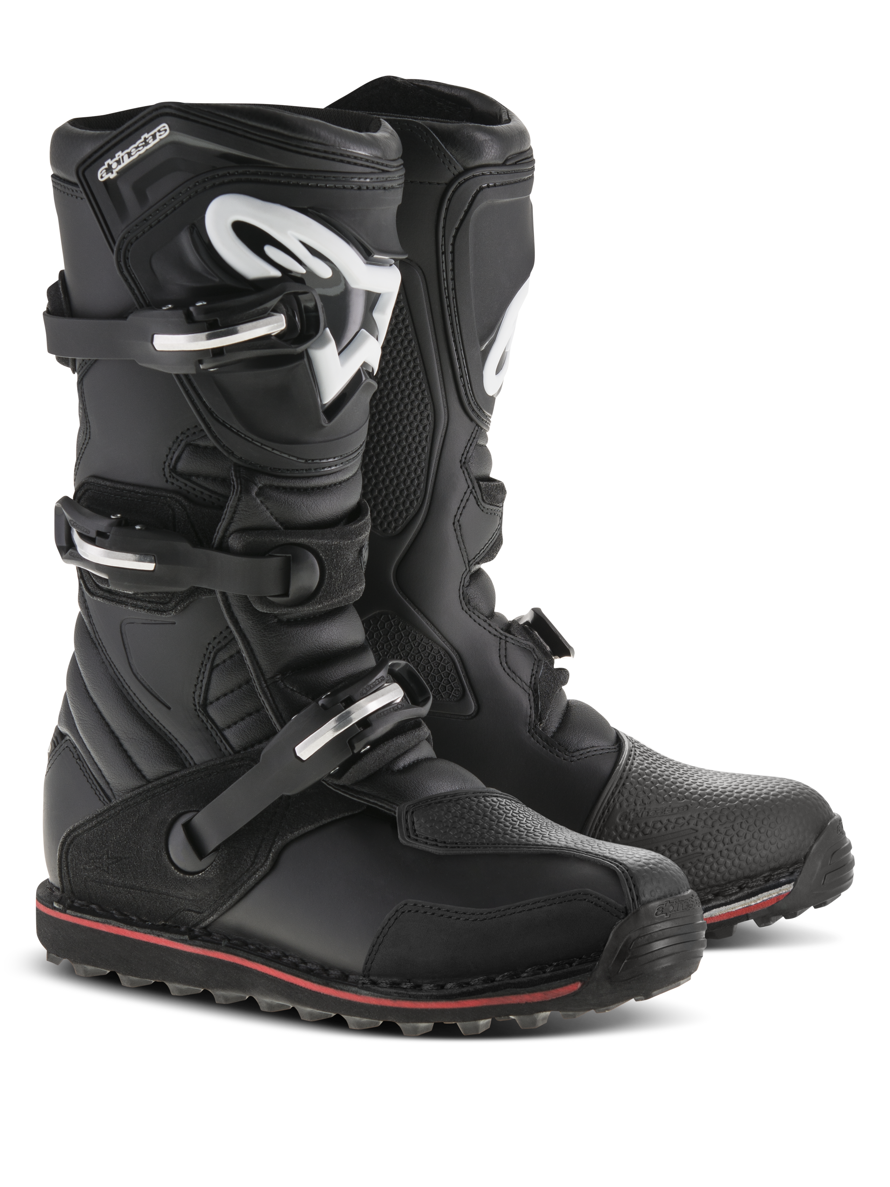 Alpinestars Tech-T laarzen, trial motorlaarzen, zwart met rode en witte accenten, voorzien van een sluitingssysteem met drie gespen, ergonomische scheenplaat met wit Astars-logo, dunne rode streep langs de zool, duurzame lederen constructie voor trial- en off-roadgebruik