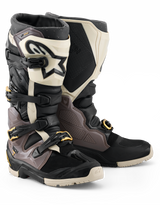 Alpinestars 2026 Tech 7 Enduro Drystar® laarzen, motorcross en enduro laarzen, zwart, donkergrijs en goud, voorzien van een robuuste TPU-schaal, snelontgrendelbare aluminium gespen met gouden accenten en een grote witte scheenplaat met een zwart logo, ontworpen voor off-road duurzaamheid.