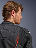 Alpinestars Dusk Airflow Leren Jas, Black Red Fluo, close-up van de bovenrug en schouder, voorzien van geperforeerd leer voor ventilatie en accordeon stretchpanelen, 'DUSK' branding detail, gedragen door een mannelijk model