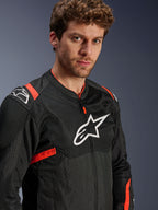 Alpinestars T-Sps Air V2 Jas, zwart met Red Fluo accenten, textiel mesh motorjas, gedragen door model, voorzien van wit Alpinestars-logo op de borst en schouders, ademende mesh-panelen, sportieve stedelijke rijstijl