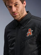 Alpinestars Ignite Air Jacket, zwart, voorzien van een traditionele overhemdkraag en ademende mesh-constructie, met een rood en goud 'A'-logo op de borst, gedragen door een mannelijk model, urbane motorkleding.