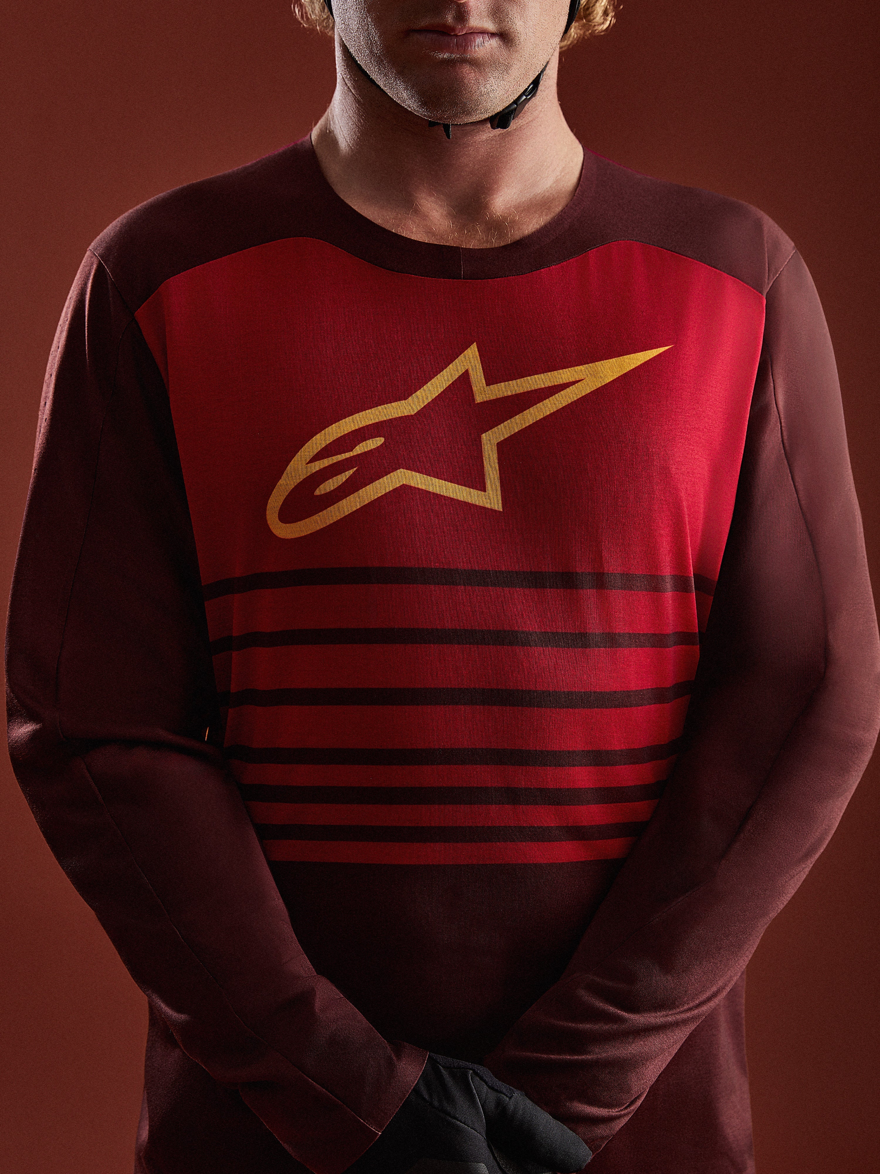 A-Dura Elite jersey met lange mouwen in bordeaux, rood borstpaneel met geel A-star logo en horizontale strepen.