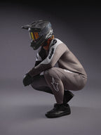 Faded gray A-Supra Elite MTB-trui en bijpassende broek met zwarte integraalhelm en crossbril voor racing.