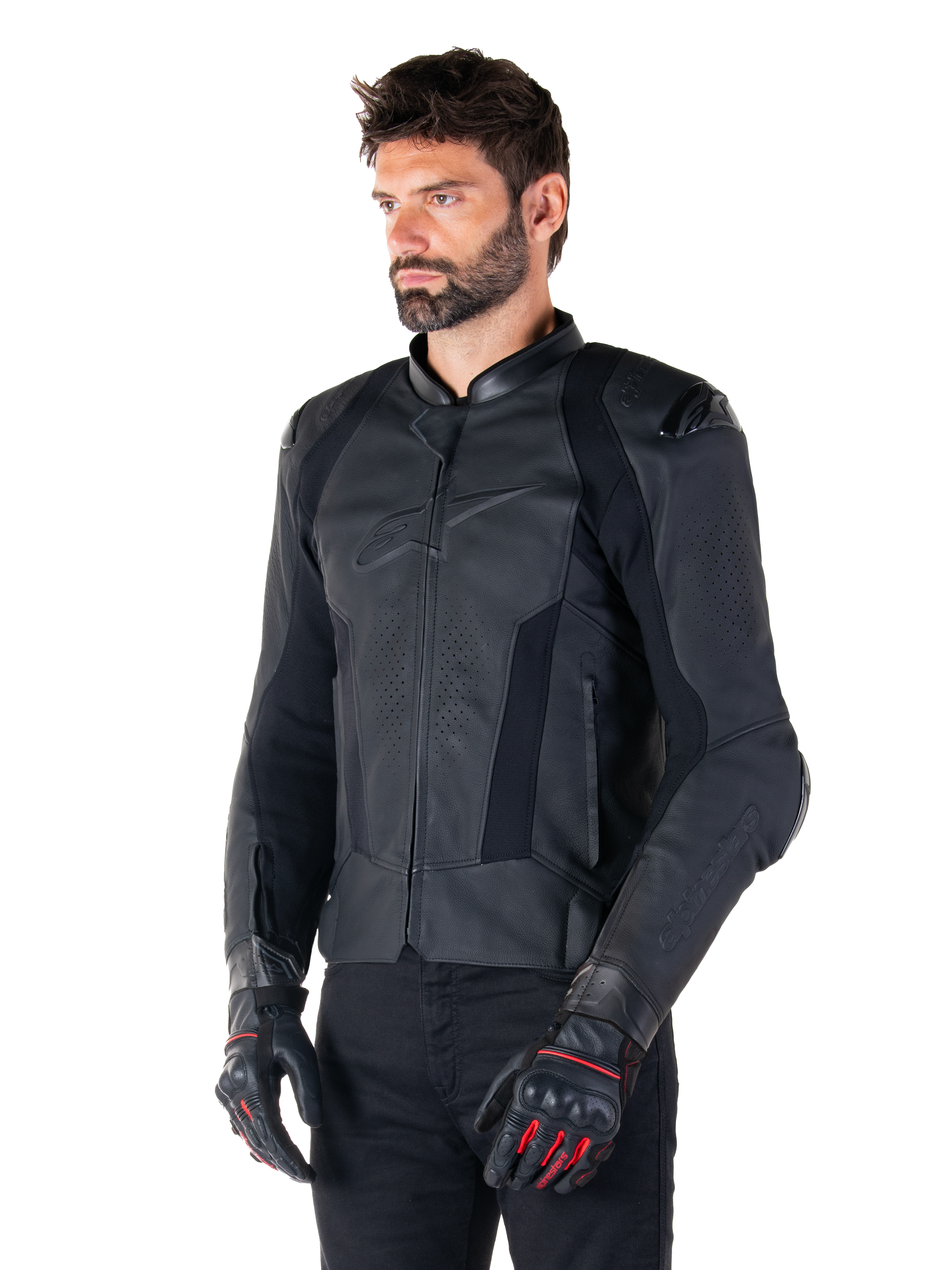 Mannelijke motorrijder met de Alpinestars Missile V3 leren jas in het zwart, premium rundleer met geperforeerde borstpanelen en externe DFS-schouderprotectoren, gecombineerd met een zwarte broek en zwart-rode racehandschoenen.