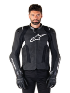 Alpinestars Missile V3 leren jas, zwart met witte logo's, gedragen door een model met zwarte motorhandschoenen, premium lederen motorracingjas met geperforeerde ventilatiepanelen en technische rijkenmerken