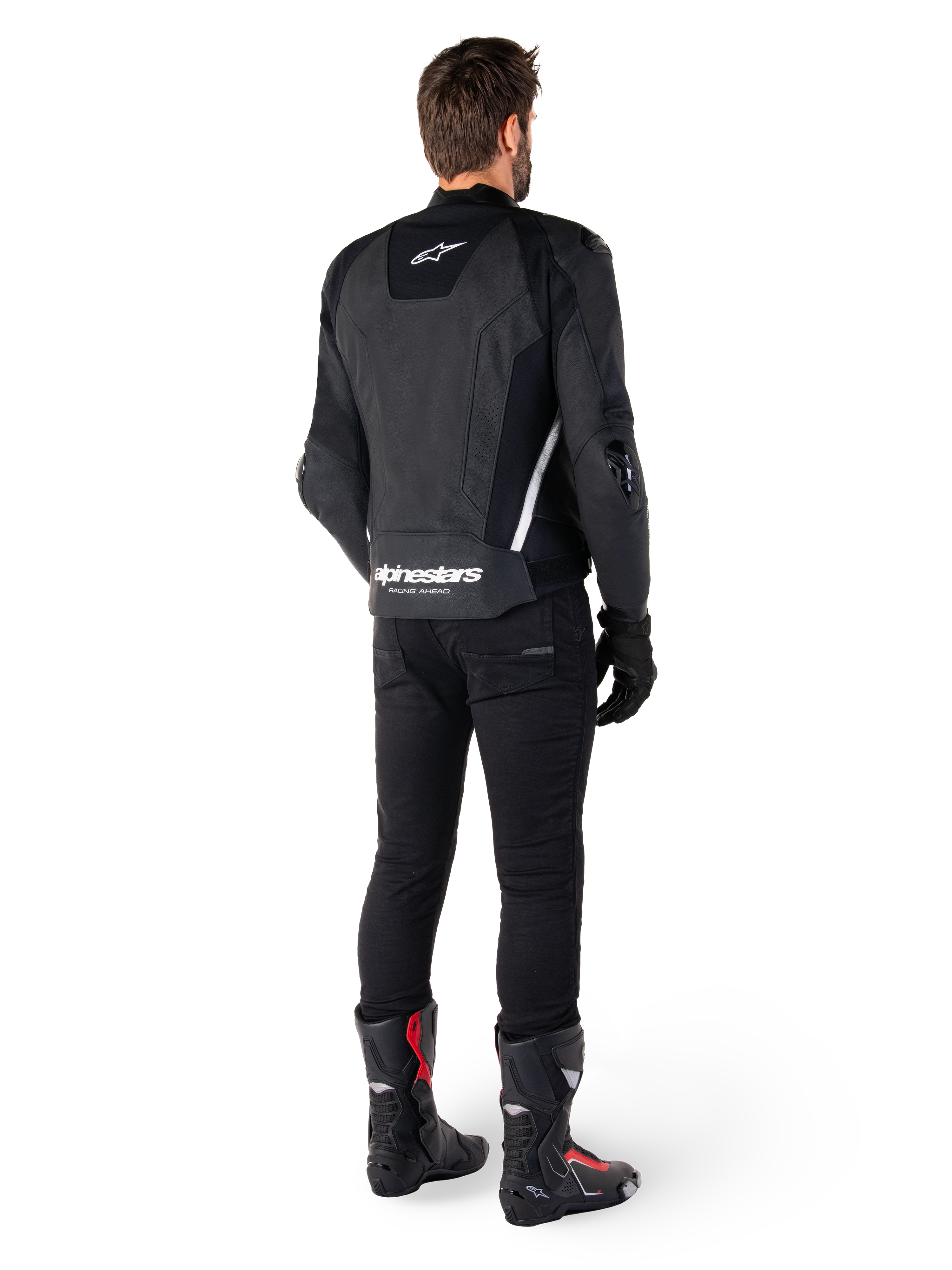 Alpinestars Missile V3 Leren Jas, zwart en wit, achteraanzicht op de rijder, met opvallende witte Alpinestars-branding op de onderrug en een klein logo op de bovenrug, gedragen met zwarte broek en racelaarzen, hoogwaardige leren constructie voor motorraces