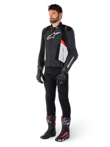Male model wearing Alpinestars Missile V3 Leather Jacket in Black White and Red Fluo, paired with black motorcycle pants, gloves, and boots, featuring premium bovine leather construction with prominent Alpinestars branding, professional racing sport aesthetic